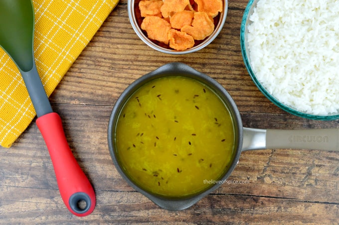 small pot of konkani daali varan, with a bowl of rice, and small bowl of crunchy vodi