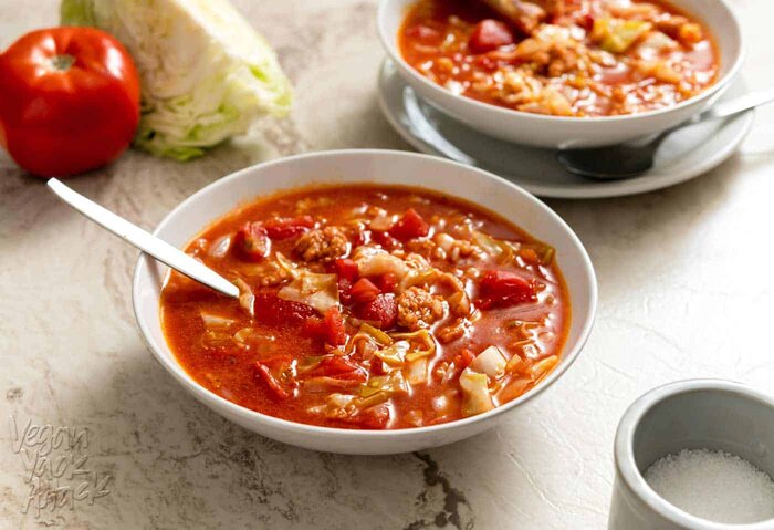 Two bowls of cabbage roll soup on a marble background