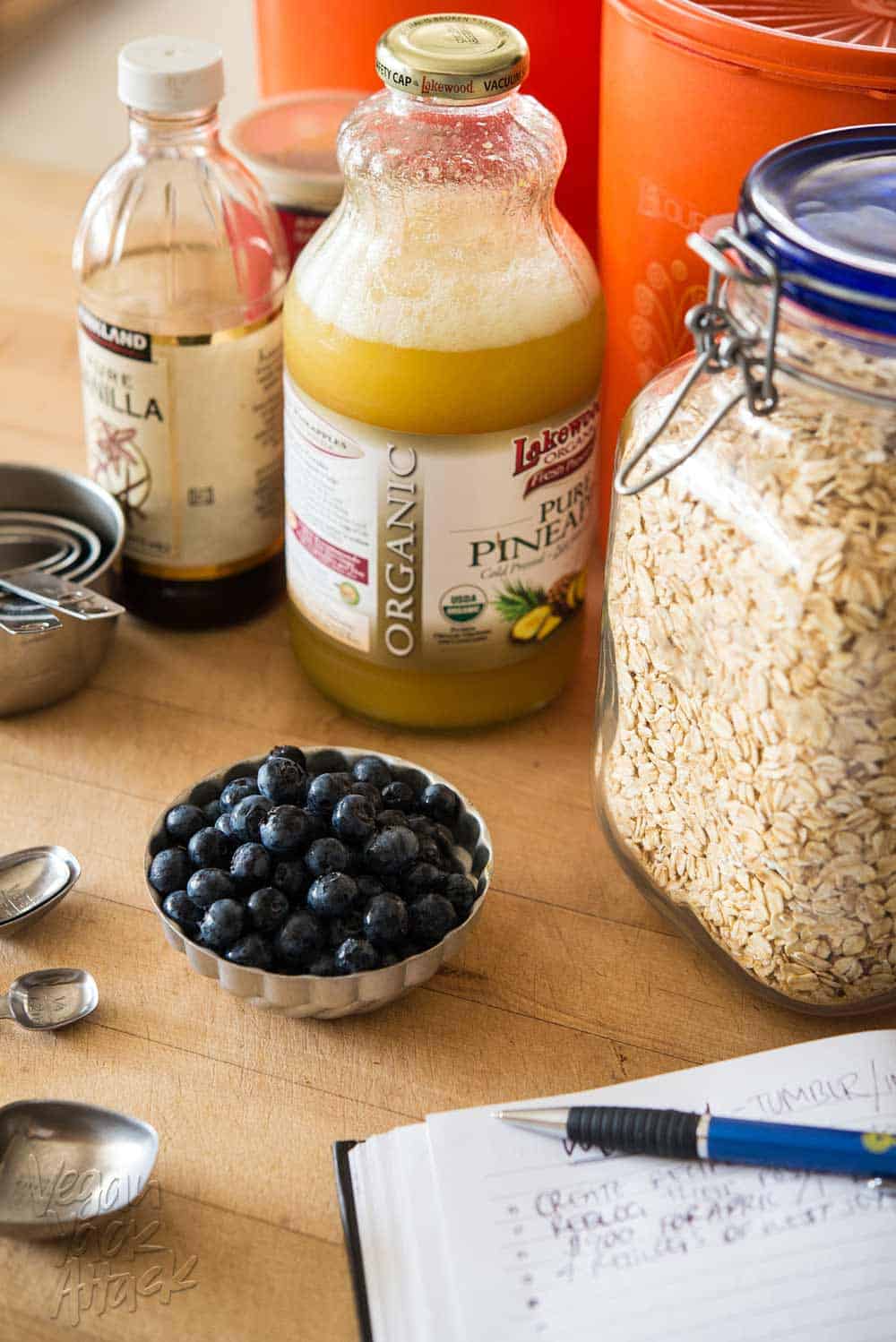 Pineapple juice, oats, vanilla, and blueberries on a kitchen island