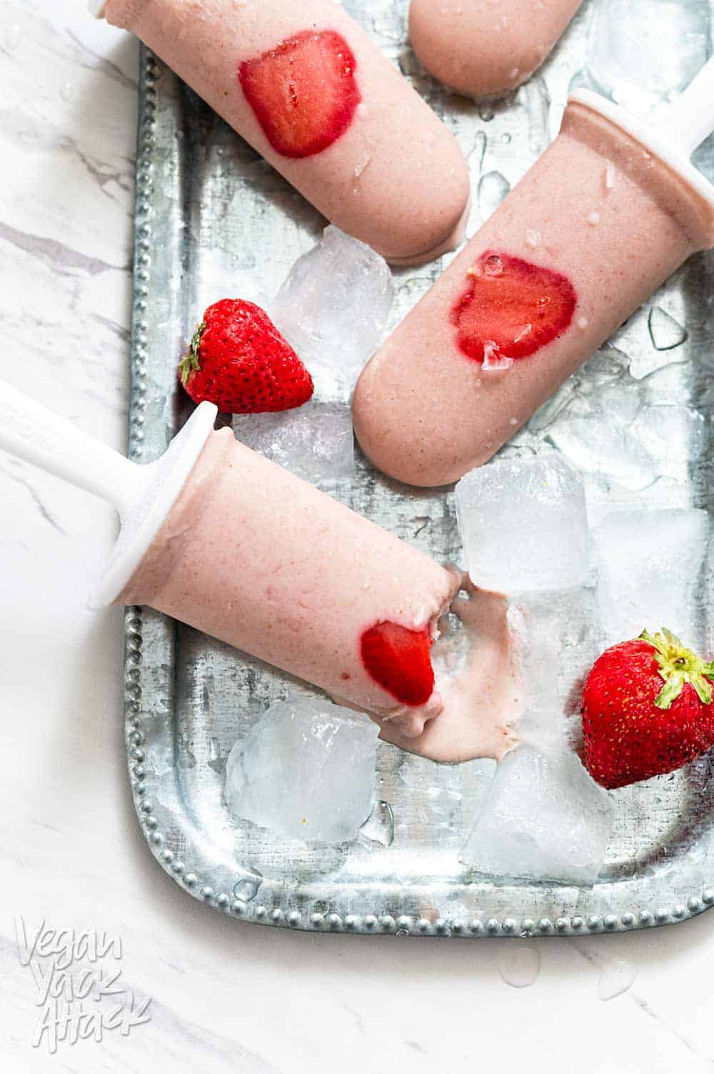 Strawberry Oat Milk Popsicles on a metal platter with ice cubes