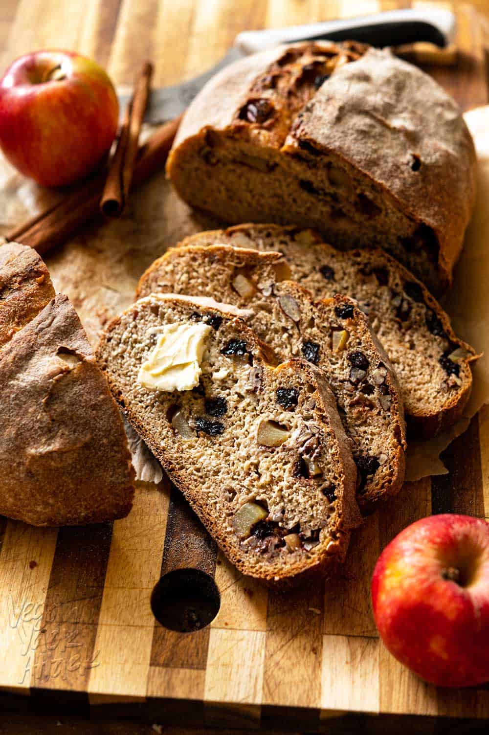 Crispy loaf of whole wheat bread partially sliced on a cutting board