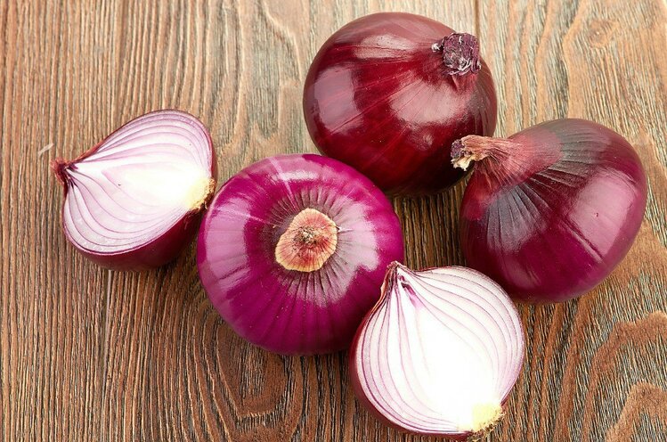 Fresh red onions on a wooden background | Dicas de Saúde