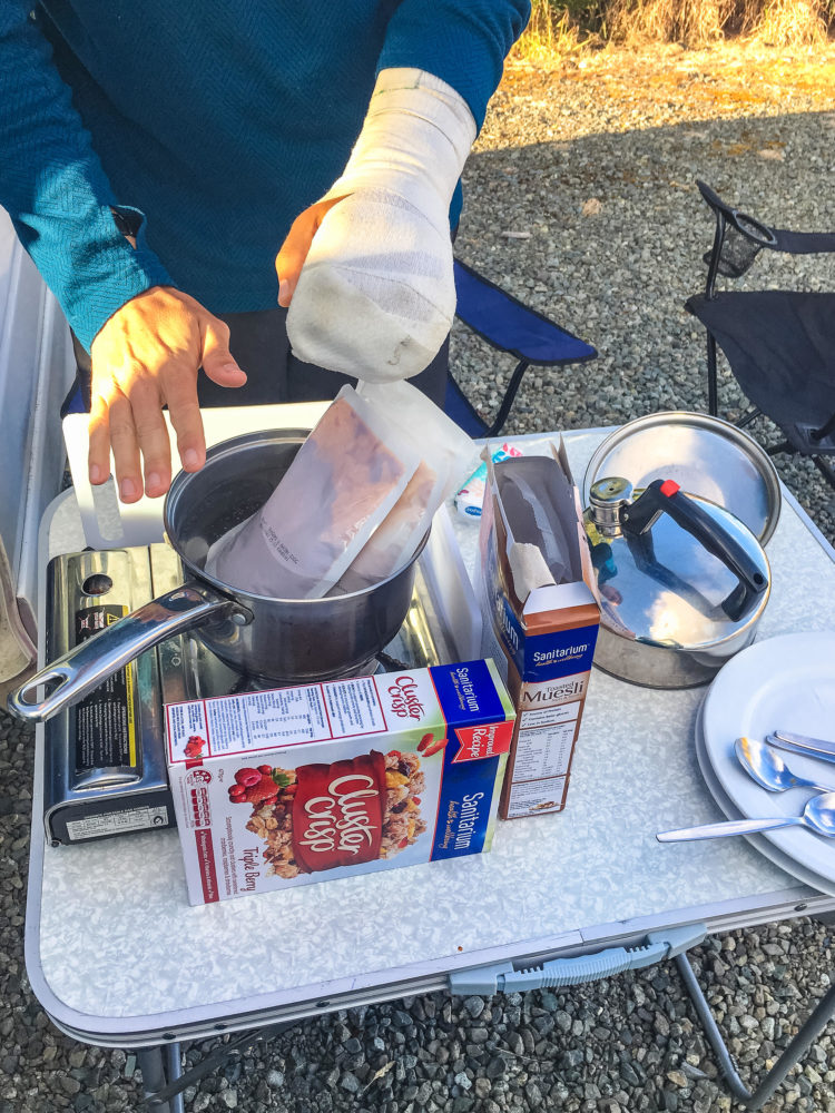 Essen wird auf einem Campingkocher mit WIndschutz gekocht