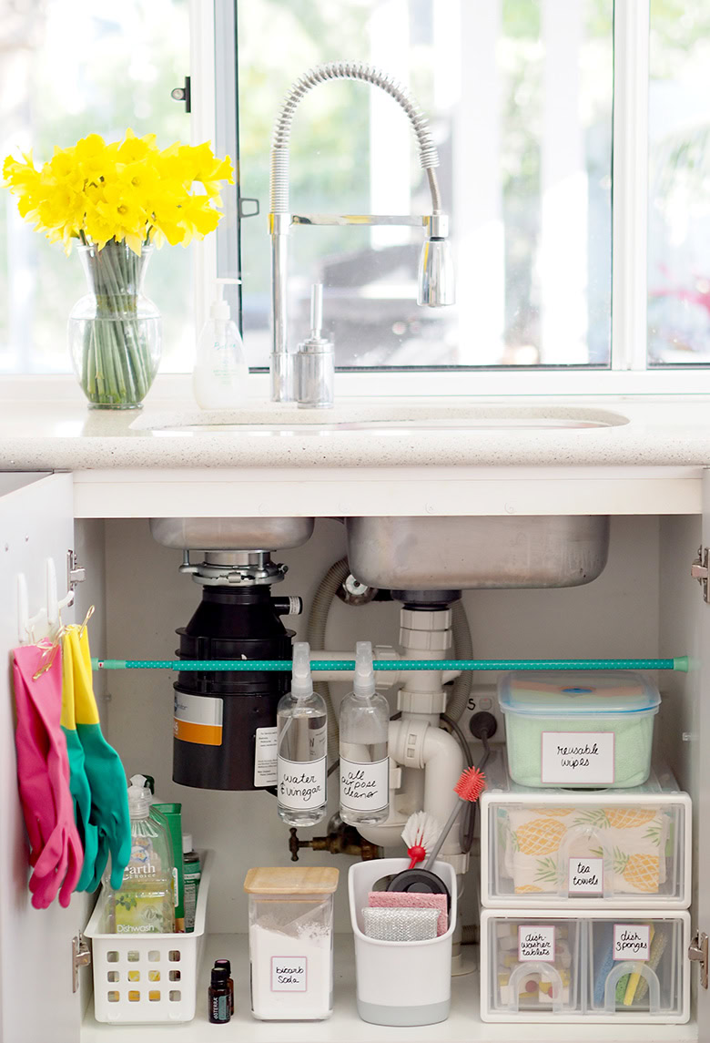 kitchen sink with view of open cabinet storing cleaning supplies