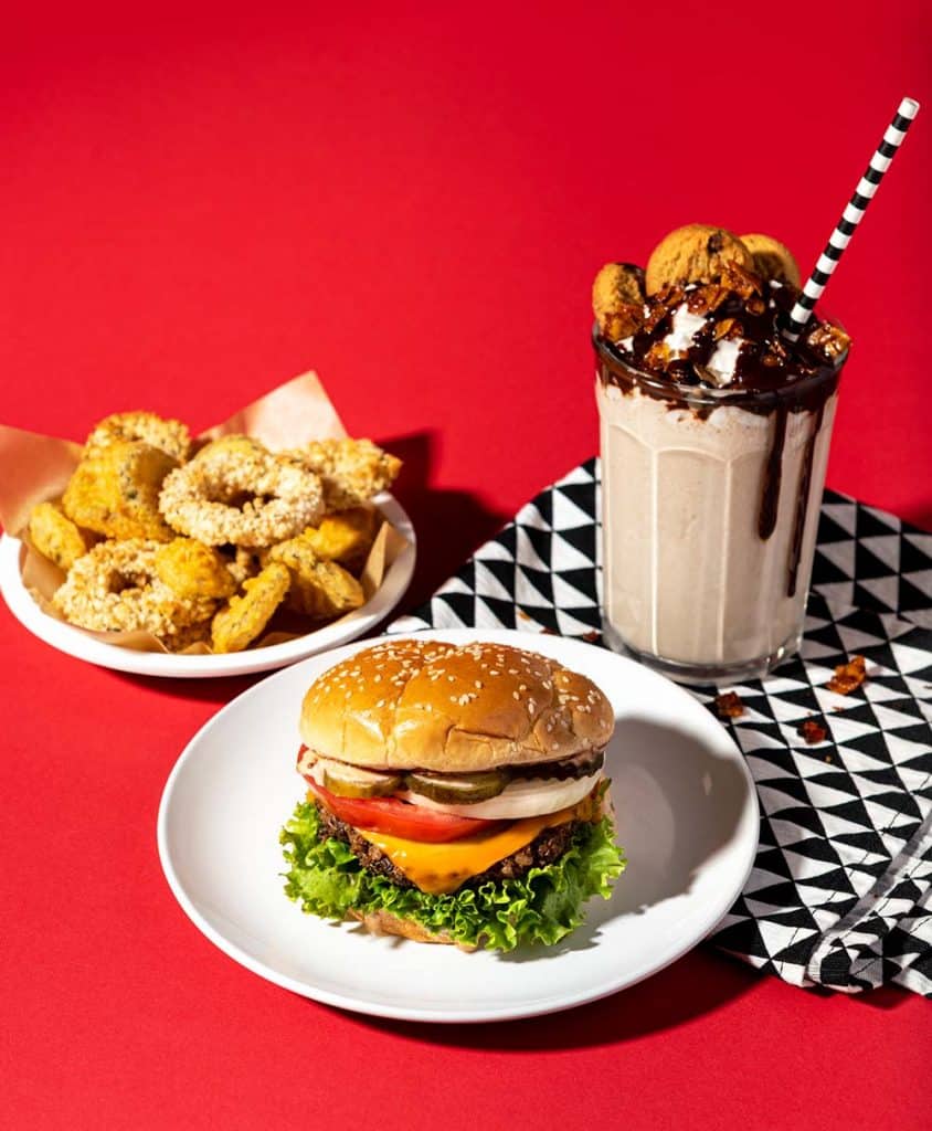 Spread opener image for the Burgers, Fries, & Shakes, Oh my! Column in the Summer 2019 issue of Vegnews Magazine, written by Joni Marie Newman.