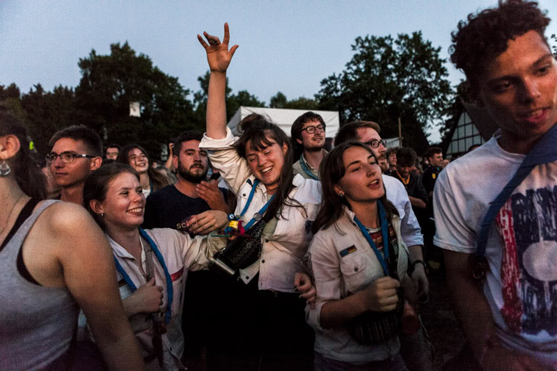 Junge Pfadfinder*innen tanzen ausgelassen zur Musik auf einem selbstorganisierten Bandfestival./ Young Boy and Girl Scouts dance exuberantly to music at a self-organised band festival.