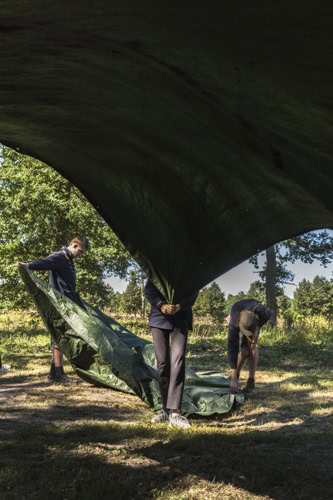 Einige Pfadfinder schütteln beim Abbau des Lagers Bodenplanen aus. / Some scouts shake out tarpaulins when dismantling the camp. Some scouts shake out tarpaulins when dismantling the camp. Camp building is an essential activity everybody takes part in.