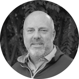 Black and white headshot of a bald man, named Justin, with a short beard.