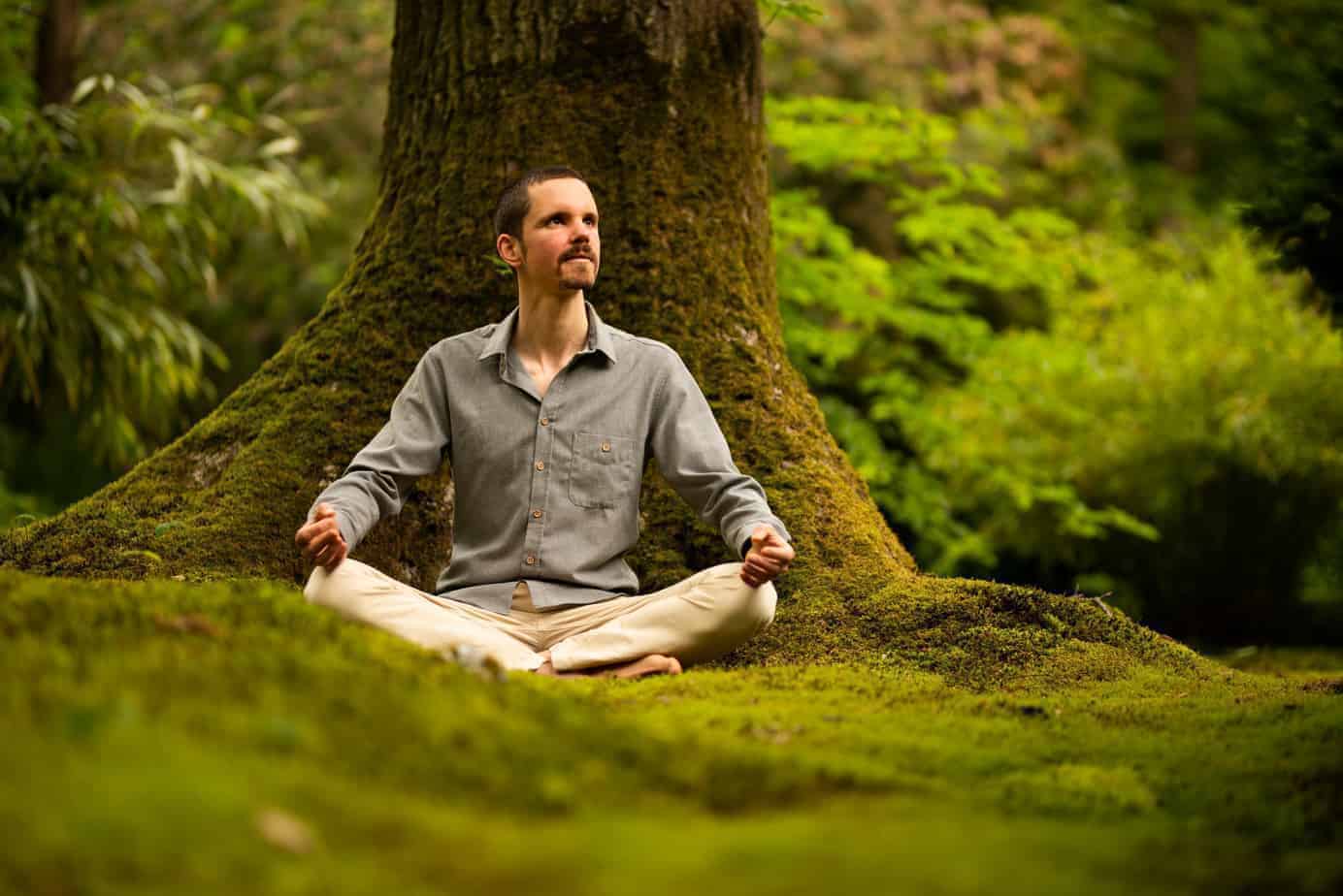 Hoe mindfulness werkt: trainer die zittend in meditatiehouding mindfulness beoefend