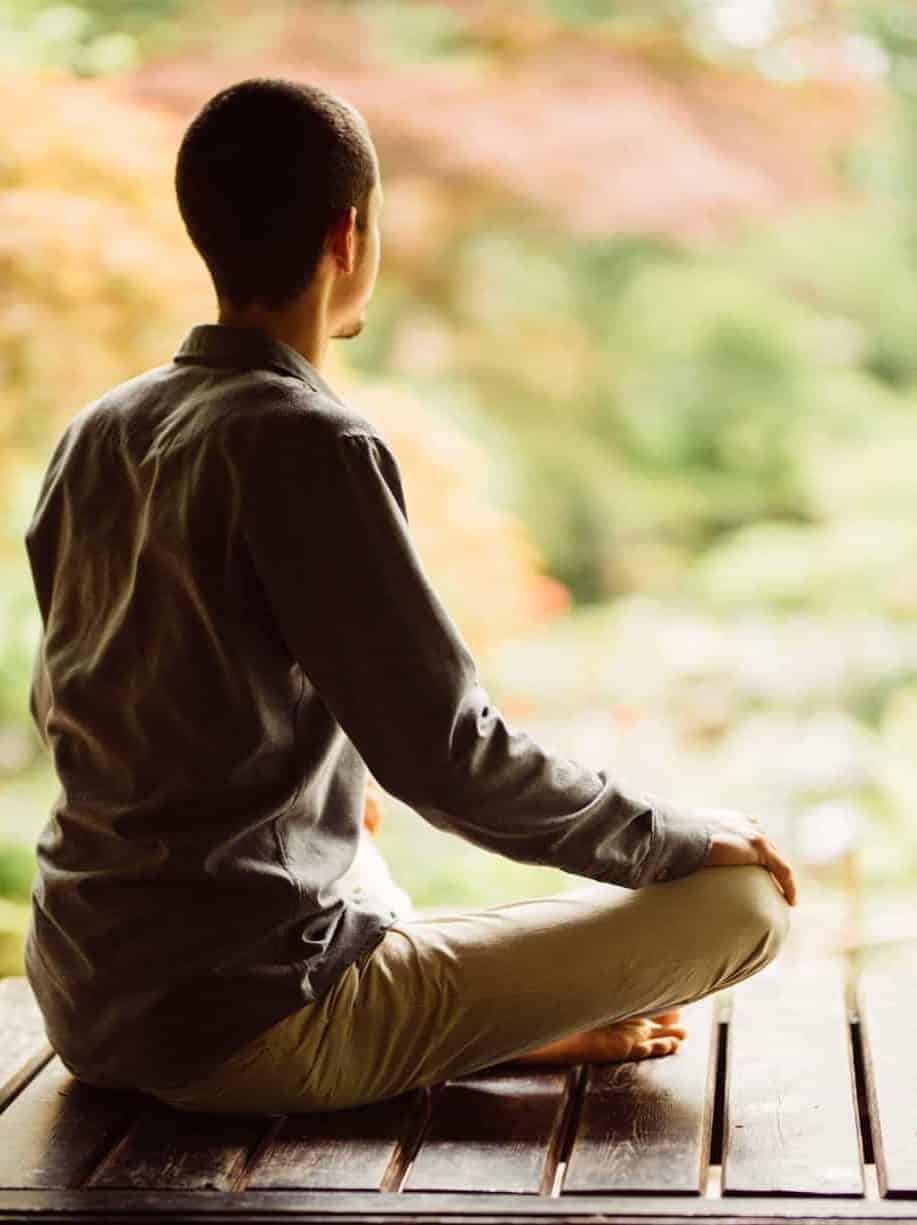 Marc van Heyningen in meditatiehouding op een houten vlonder in de Japanse tuin in Clingendael.