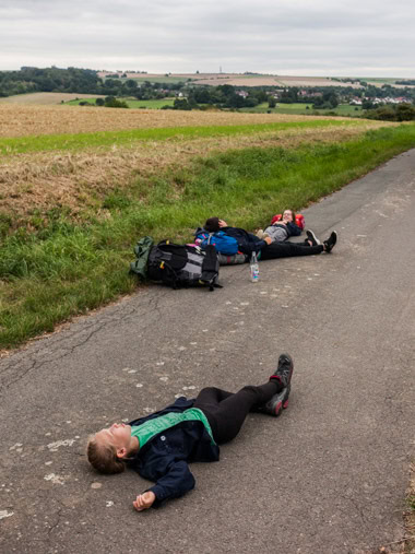 Junge Pfadfinderinnen machen eine Pause während einer Wanderung und liegen auf einem Feldweg bei Immenhausen. / Young female scouts take a break during a hike and lie on a field path near Immenhausen.