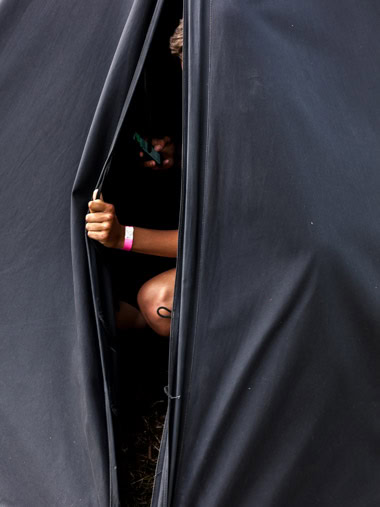 Ein Pfadfinder wirft im Zelt einen Blick auf sein Smartphone. / A boy scout takes a look at his smartphone in the tent.