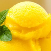 Mango lime sorbet in a white bowl with mint garnish
