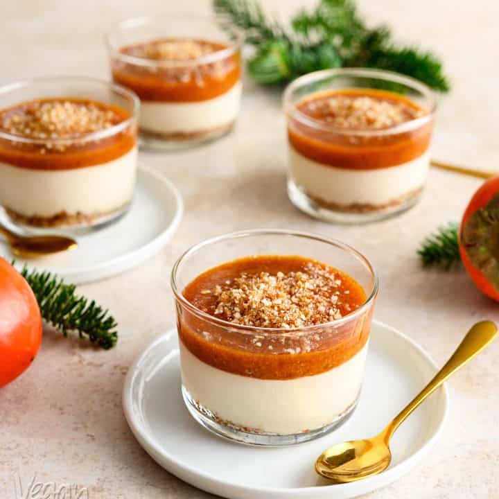 Persimmon cheesecake in a glass, on a white saucer with gold spoon