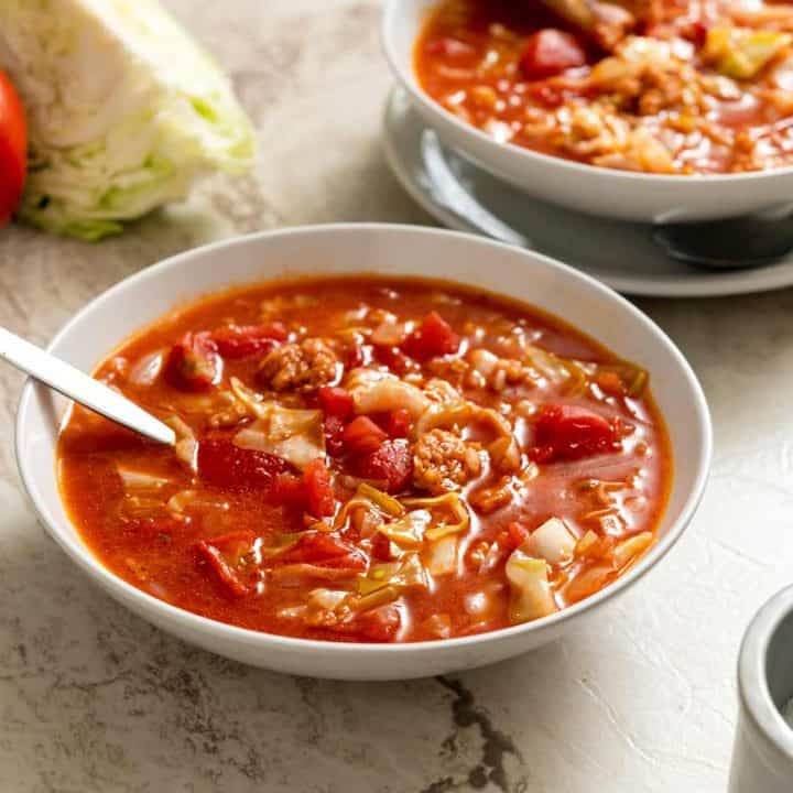 Two bowls of cabbage roll soup on a marble background