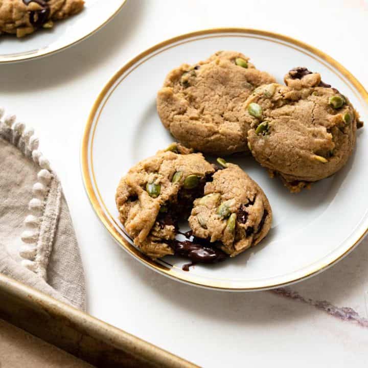 Cookies on a baking sheet with plate of cookies next to it