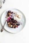 plate of gluten free blueberry crisp with coconut ice cream