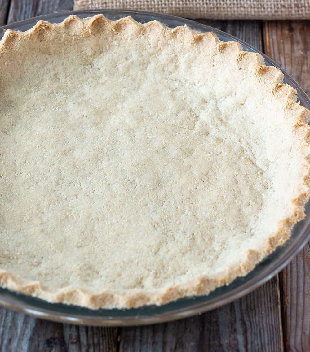 Finished baked almond pie crust in glass pie plate, made with almond flour, vegan butter, maple syrup. salt. and vanilla