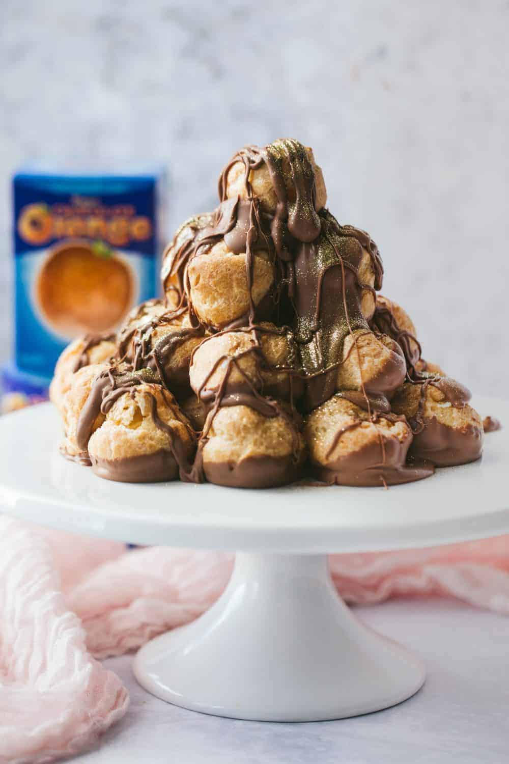 Uma torre de profiterole coberta com molho de chocolate.