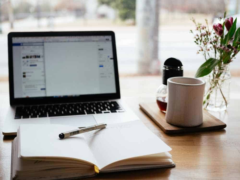 A photo of a laptop and a notebook. Photo by Nick Morrison on Unsplash