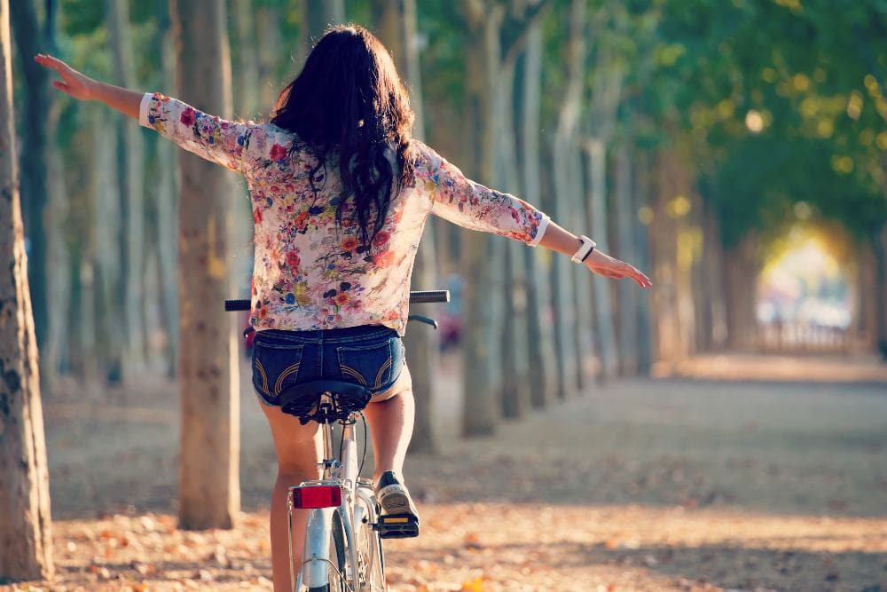 Girl riding bike down path of trees