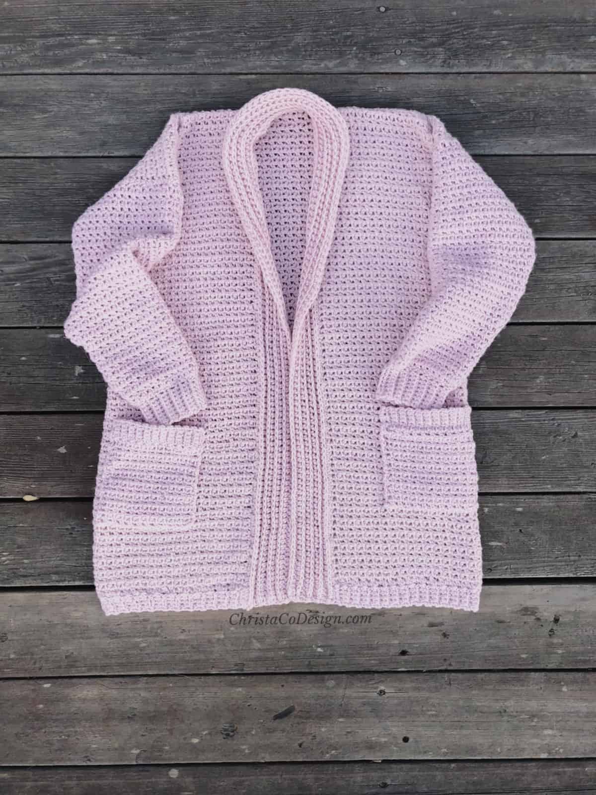 picture of cozy crochet cardigan in pink laid flat on boards