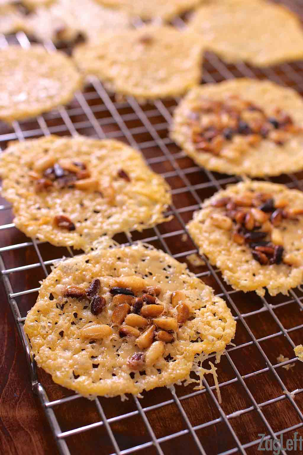 Parmesan cheese crisps on a cooling rack topped with toasted pine nuts