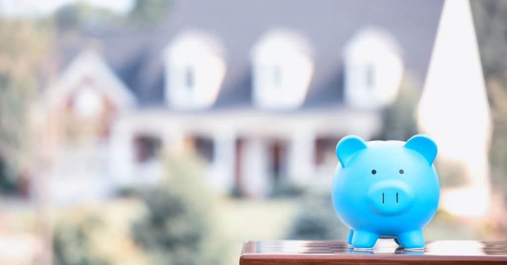 Blue piggy bank sitting in front of large home.