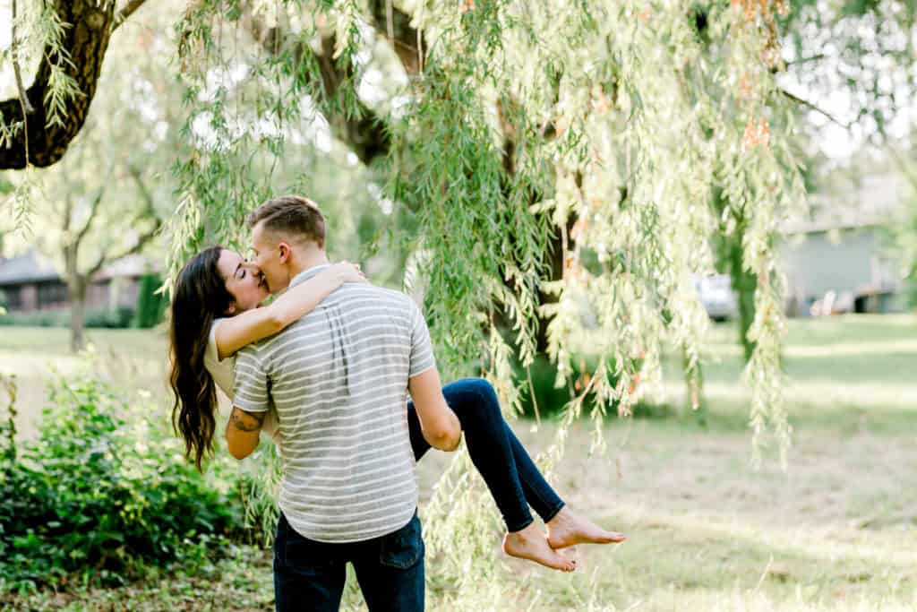 engagement session couple kissing he is lifting the girl