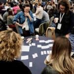 Confab 2019 attendees standing around tables looking at notecards