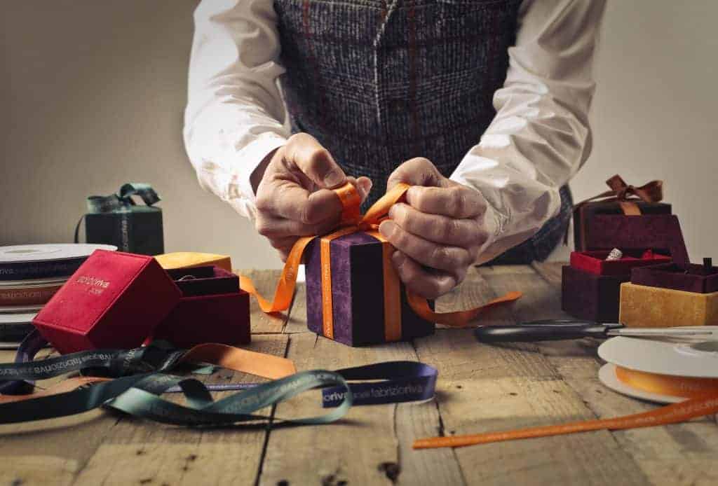 man wrapping box with bow