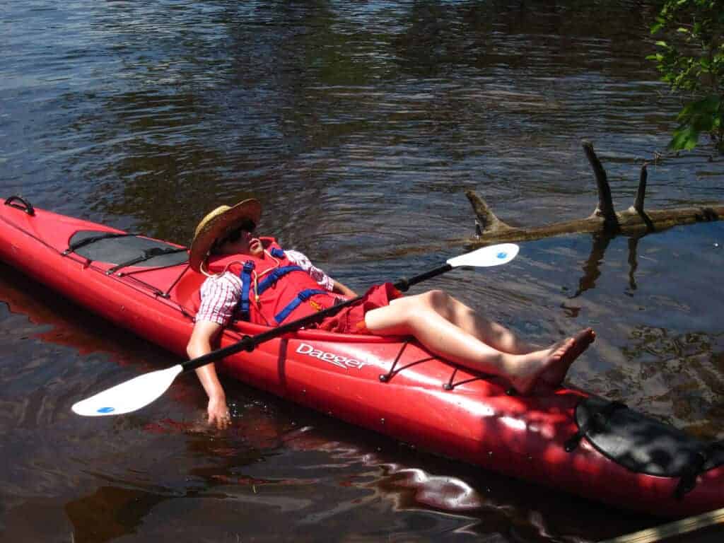A lazy kid snoozing on a red kayak