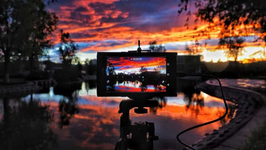 A colorful sunset over a lake with the LCD screen of a DSLR camera in the foreground.