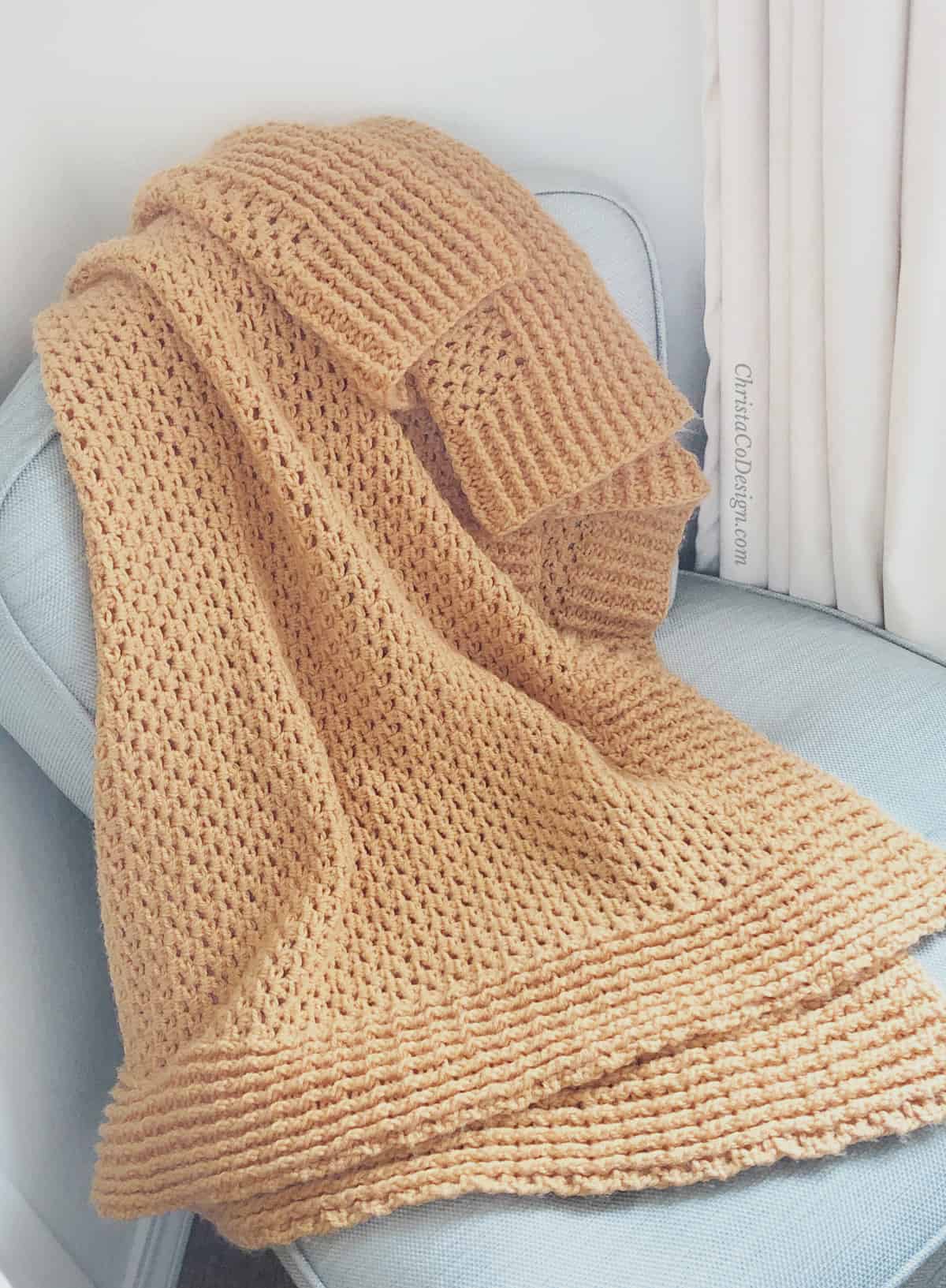 picture of crochet ribbed throw blanket in orange on blue chair