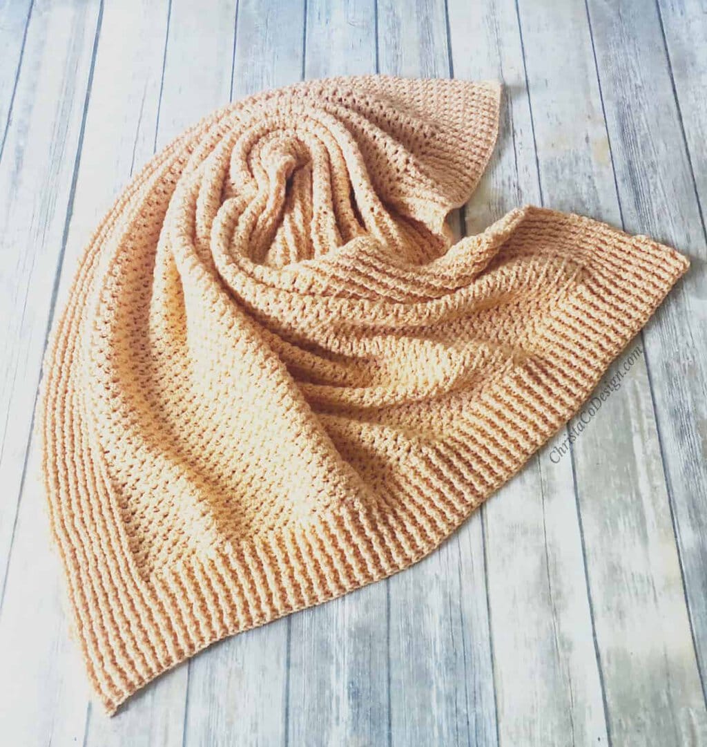 picture of orange crochet blanket twisted on wood floor