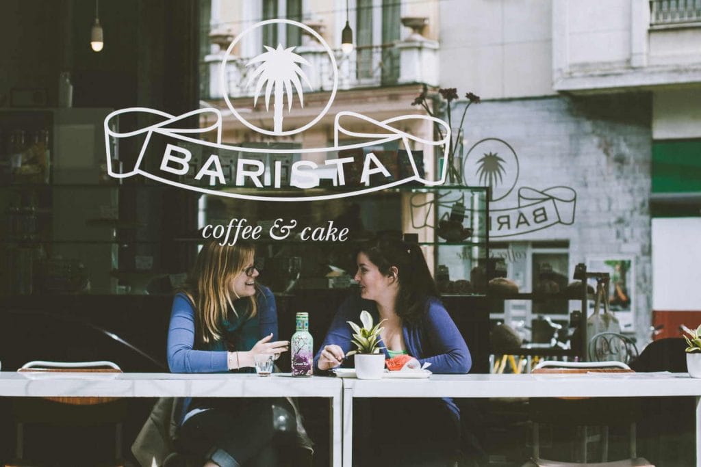 Two women chatting over coffee in a cafe window. Photo by Franky Van Bever on Unsplash