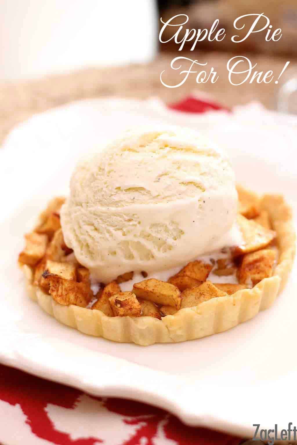 A mini apple pie topped with a scoop of vanilla ice cream