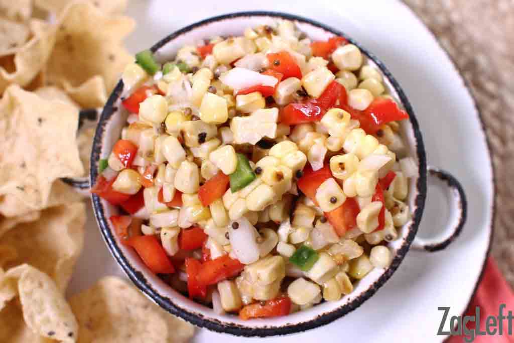 An overhead view of a bowl of corn salsa plated with tortilla chips