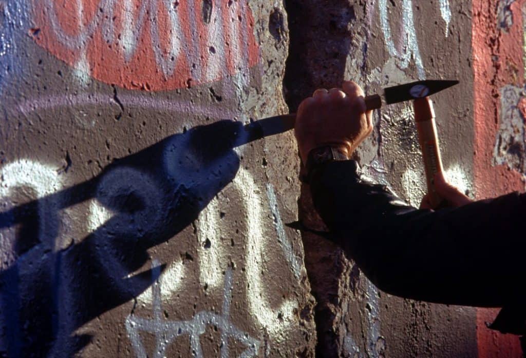 A man chips off part of the Berlin Wall, which is covered with graffiti.