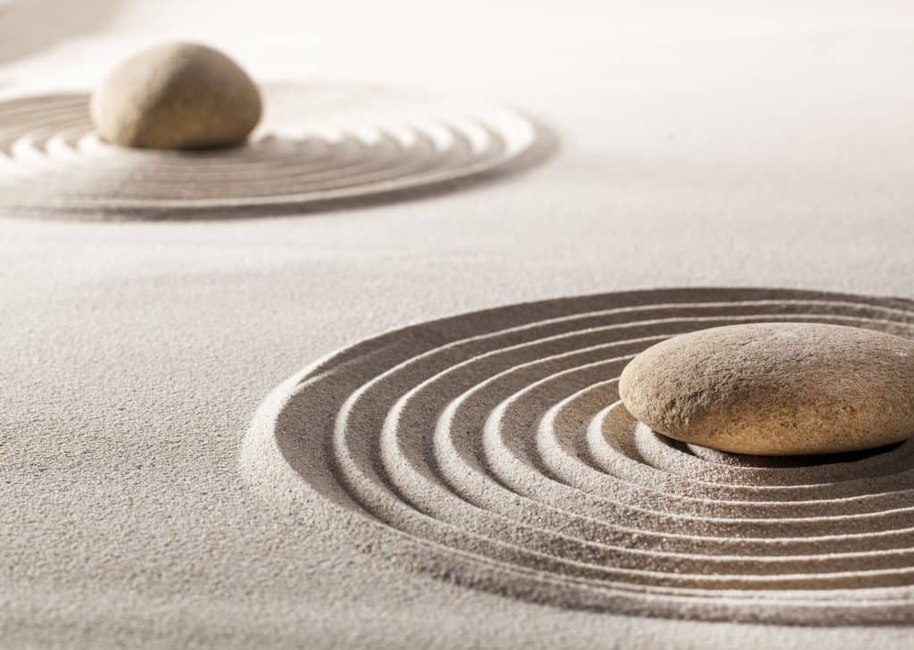 stones or pebbles in the middle of pure waves in sand for concept of tranquillity or wellbeing