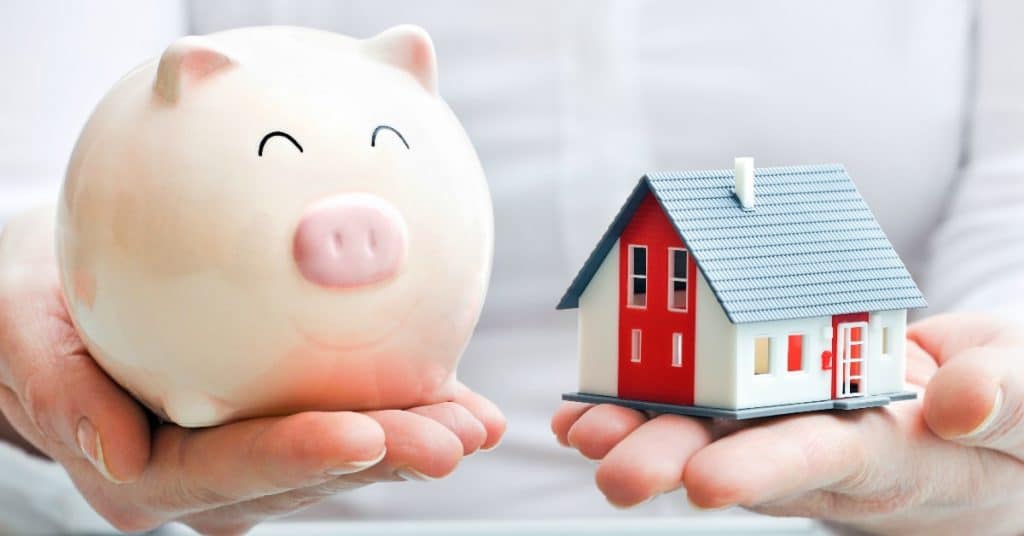 Image of a woman holding a piggy bank and a small model of a home. Which is better, a 15-year or a 30-year mortgage?
