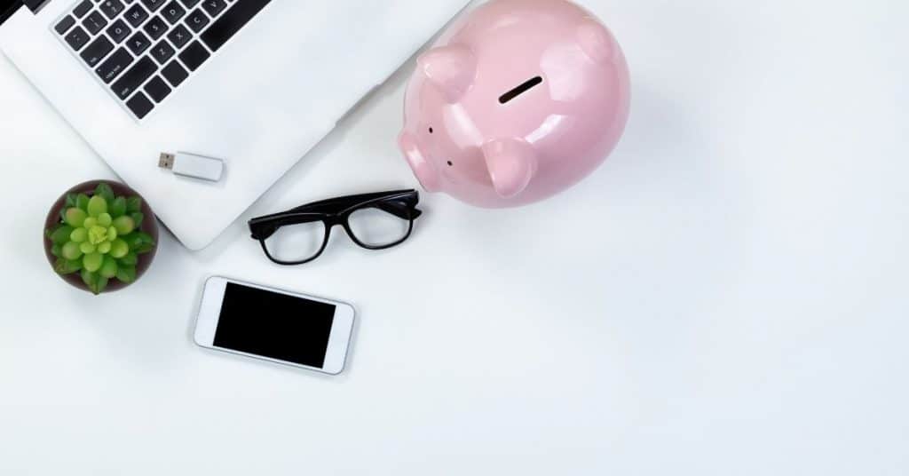 Piggy bank on desk top near computer and phone - Financial Goals
