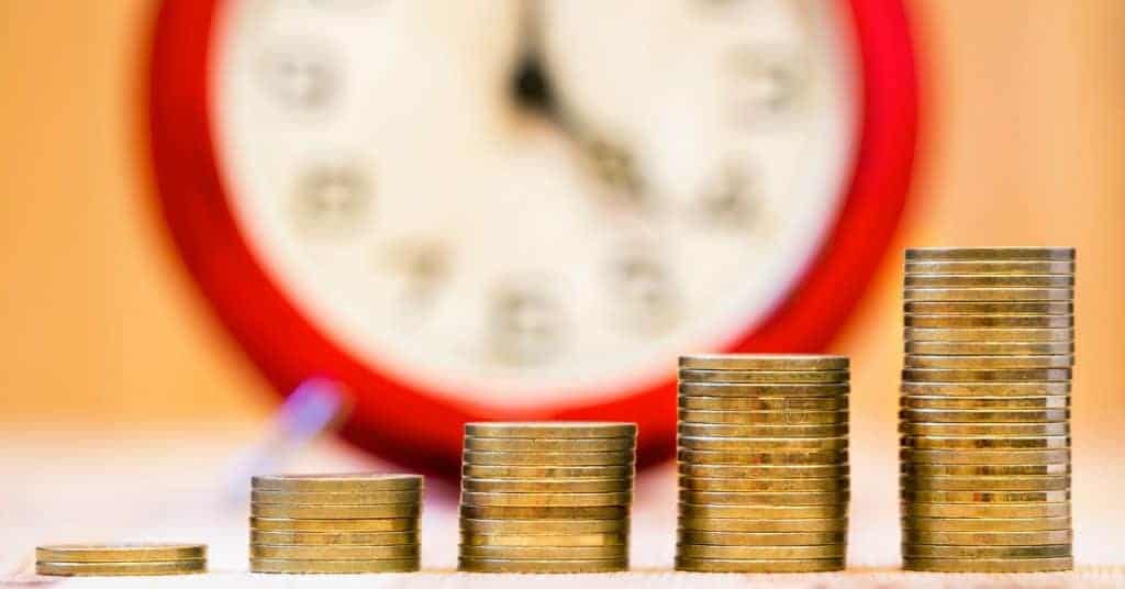 Image of a clock in the background and increasing stacks of coins, text overlay "Real-World Examples on the Power of Compounding Interest"
