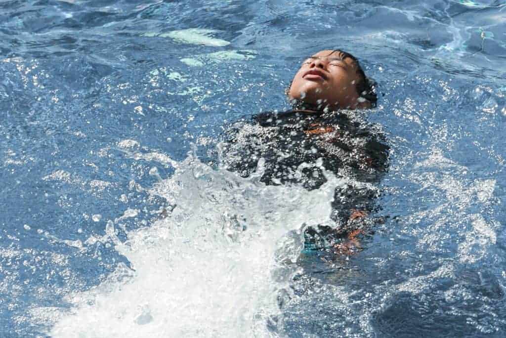 boy swimming backwards kicks in pool