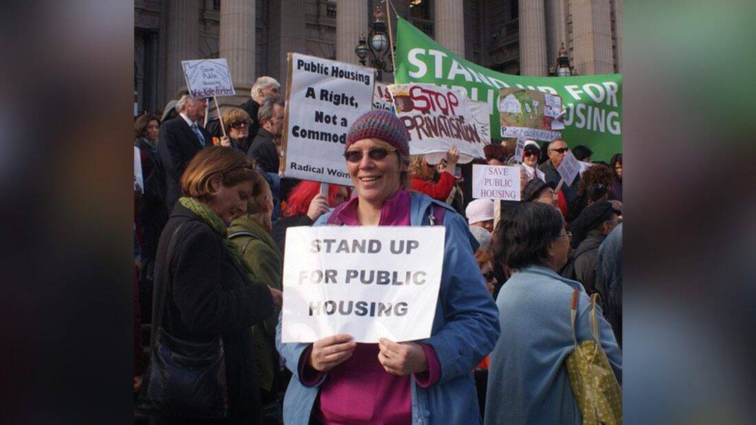 Woman holding "Stand up for public housing" sign