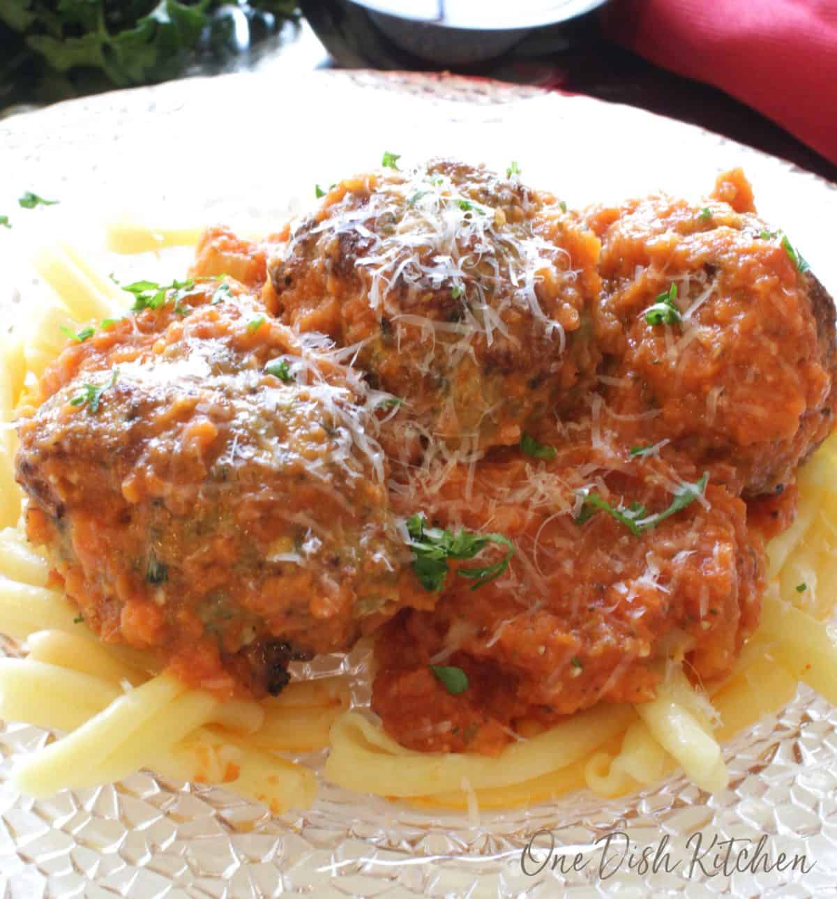 a plate of spaghetti and meatballs topped with parmesan cheese.