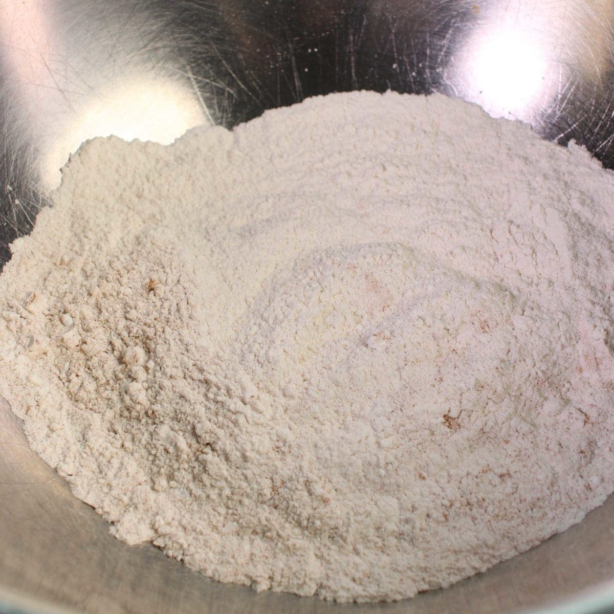 a silver mixing bowl filled with flour