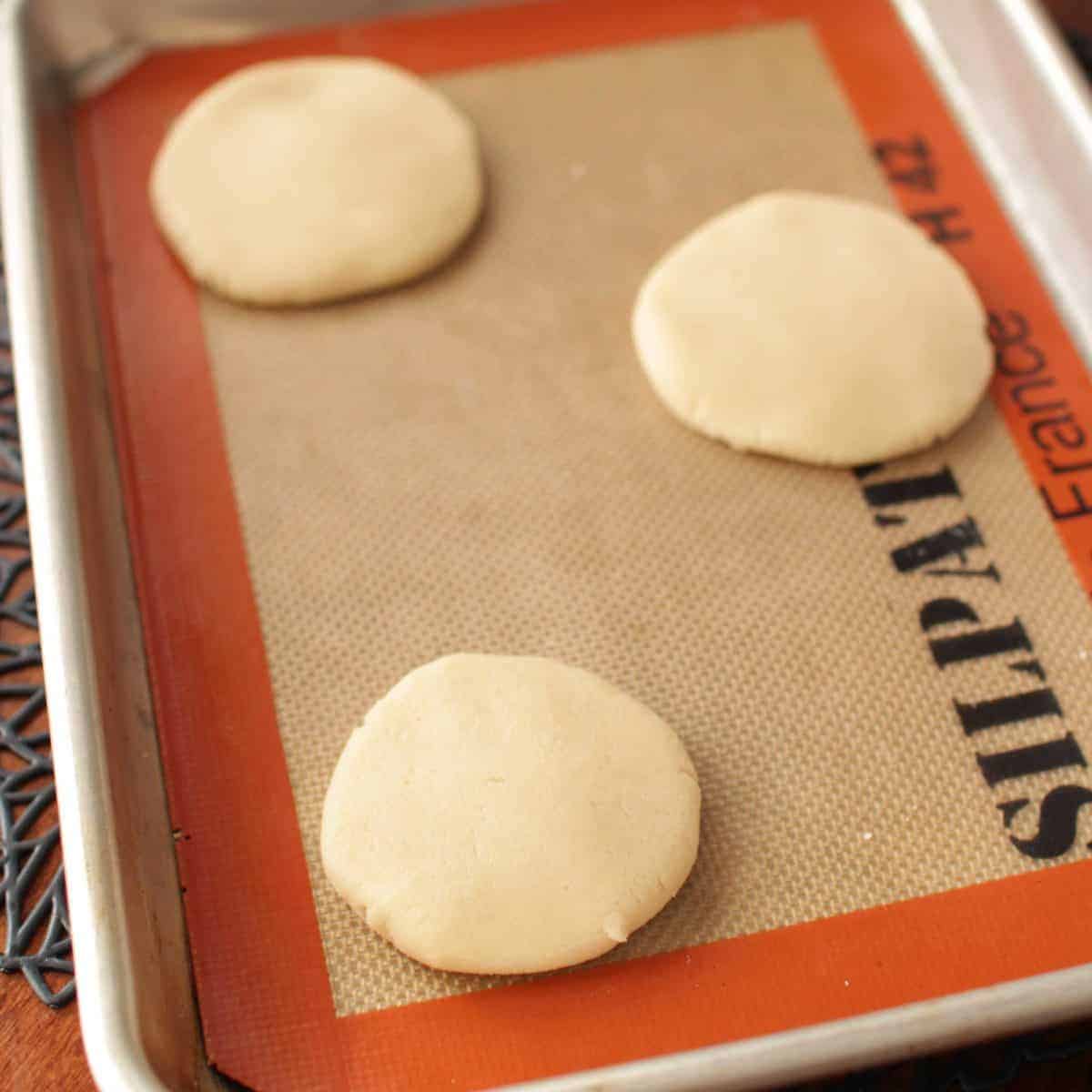 cookie dough flattened on a baking sheet.