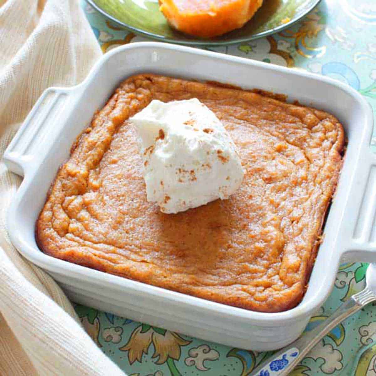 Sweet potato pie made with sweet potatoes cooked in an instant pot topped with whipped cream in a small baking dish