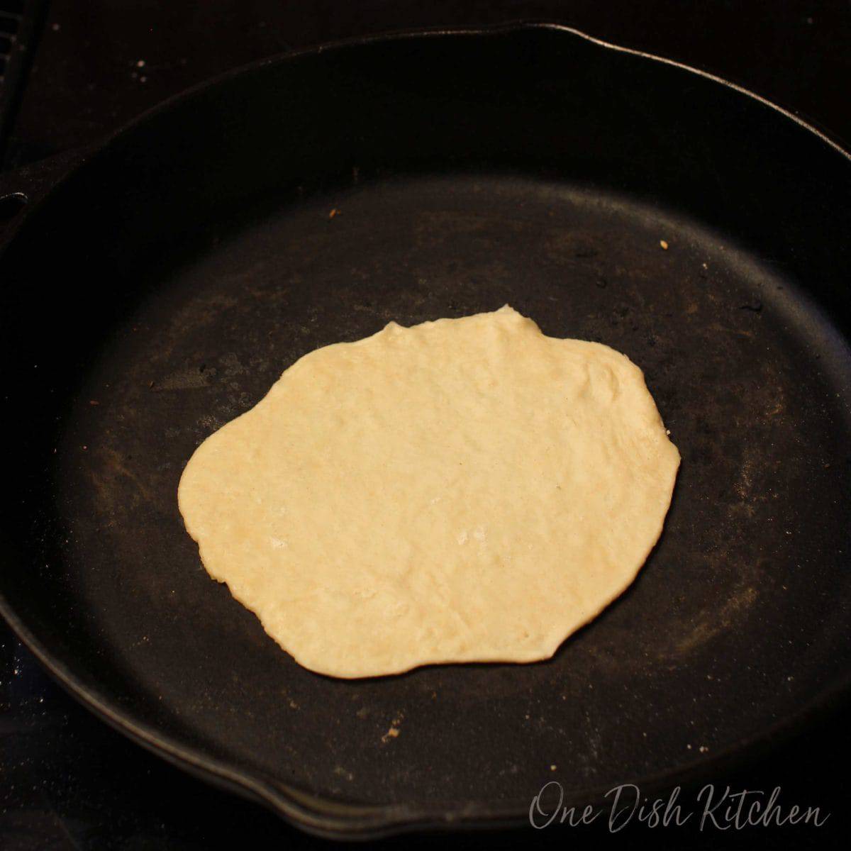 one tortilla in a cast iron skillet